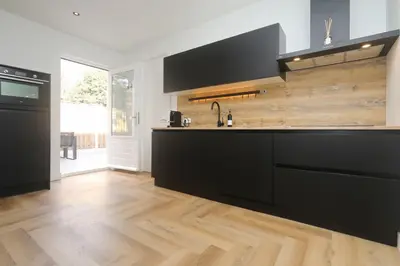 a kitchen with black cabinets and a wooden floor at Steenhof Beach House in Noordwijk