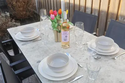 a table with plates and a bottle of wine and flowers at Steenhof Beach House in Noordwijk