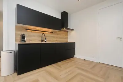 a kitchen with black cabinets and a sink at Steenhof Beach House in Noordwijk