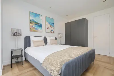 a bedroom with a large bed and two paintings on the wall at Steenhof Beach House in Noordwijk