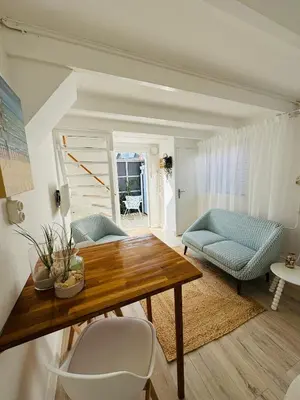 a living room with a wooden table and blue chairs at Zeeschelpje in Noordwijk aan Zee
