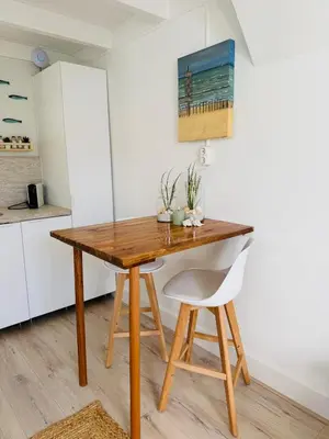 a kitchen with a wooden table and a chair at Zeeschelpje in Noordwijk aan Zee