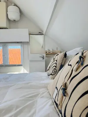 a white bed in a room with a window at Zeeschelpje in Noordwijk aan Zee