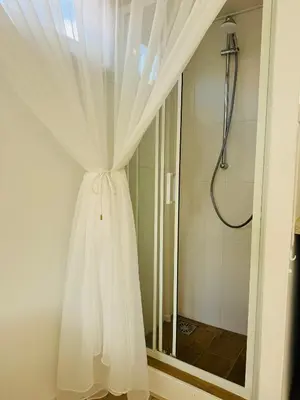a white curtain in a bathroom with a shower at Zeeschelpje in Noordwijk aan Zee