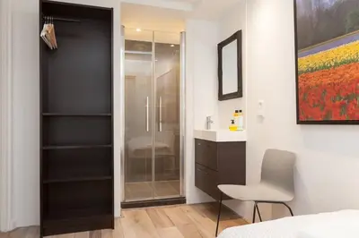 a bathroom with a glass shower and a white chair at Lovely 4P-apt near Canals - Utrecht City Centre in Utrecht