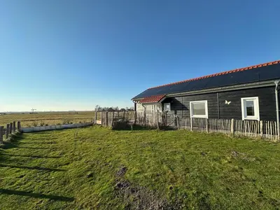 a house in a field next to a fence at BB Saari in De Woude