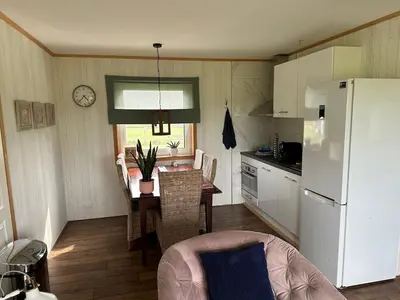a kitchen with a table and a white refrigerator at BB Saari in De Woude