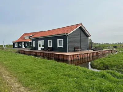 a house on a boardwalk next to a river at BB Saari in De Woude
