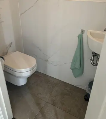 a bathroom with a white toilet and a sink at Wellness Appartement Duinpoort in Castricum