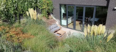 a house with a patio with a chair in a yard at Wellness Appartement Duinpoort in Castricum