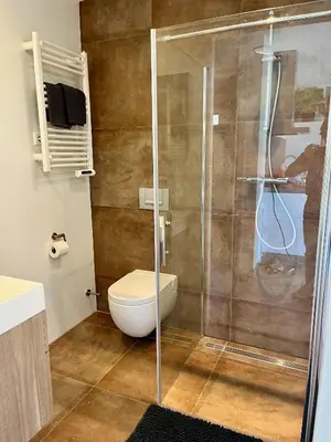 a bathroom with a toilet and a glass shower at BeachHouse AAN ZEE in Noordwijk aan Zee