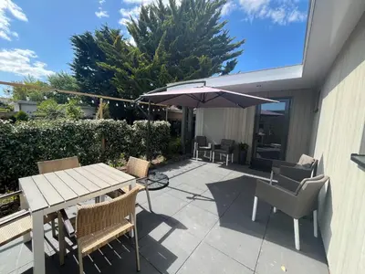 a patio with a table and an umbrella and chairs at BeachHouse AAN ZEE in Noordwijk aan Zee