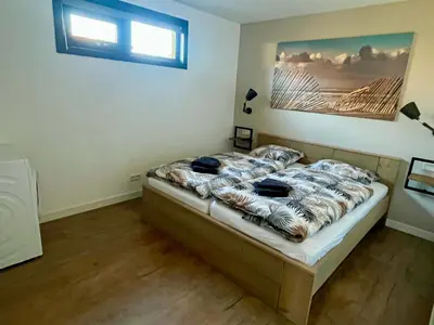 a bedroom with a bed with a painting on the wall at BeachHouse AAN ZEE in Noordwijk aan Zee