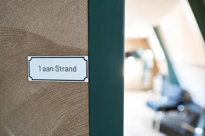 a wooden door with a sign that reads i am stand at 1 aan Strand in Egmond aan Zee