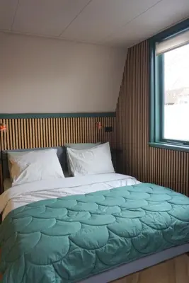 a large bed in a bedroom with a window at 1 aan Strand in Egmond aan Zee