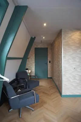 an attic room with chairs and a green door at 1 aan Strand in Egmond aan Zee