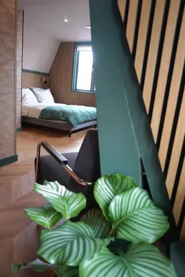a room with a bed and a chair with a plant at 1 aan Strand in Egmond aan Zee
