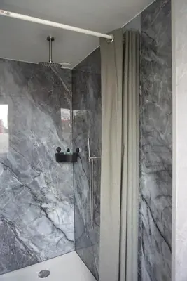 a bathroom with a shower with a marble wall at 1 aan Strand in Egmond aan Zee