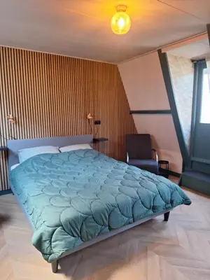 a bedroom with a large bed and a chair at 1 aan Duin in Egmond aan Zee