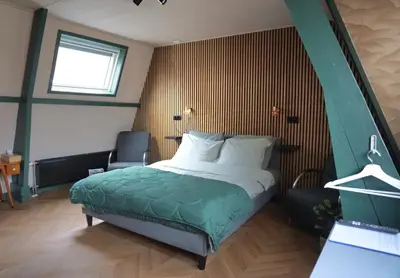 a bedroom with a bed and a chair in it at 1 aan Duin in Egmond aan Zee