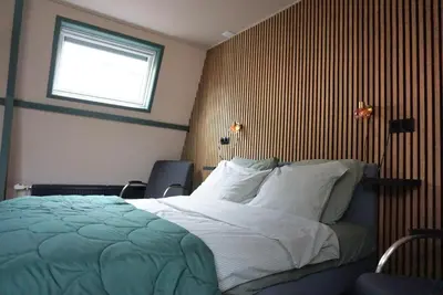 a bedroom with a large bed with a window at 1 aan Duin in Egmond aan Zee