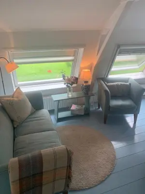 a living room with a couch and a chair and a window at De Vink Bed & Breakfast in Abcoude