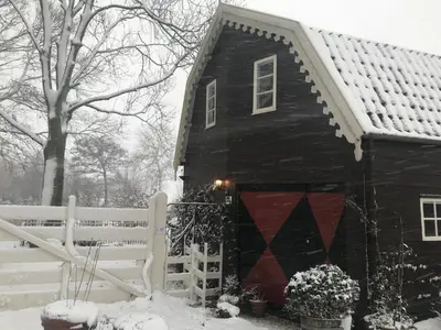 a black house with a red door in the snow at De Vink Bed & Breakfast in Abcoude