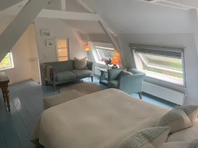 a bedroom with two beds and a couch and a chair at De Vink Bed & Breakfast in Abcoude