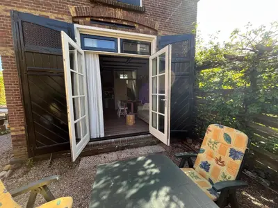 an open patio door with a table and chairs at Het Koetshuis in Gouda