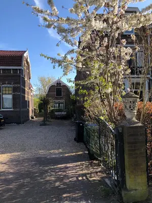 a tree in front of a house with a fence at Het Koetshuis in Gouda