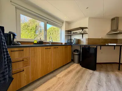 a kitchen with wooden cabinets and a black refrigerator at Holiday Home Vijfhuizen 2pers in Vijfhuizen