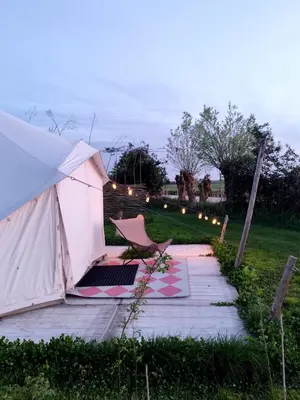 a tent with a chair on a wooden deck at Voedselbos Camping Koperwiek in Hazerswoude-Dorp