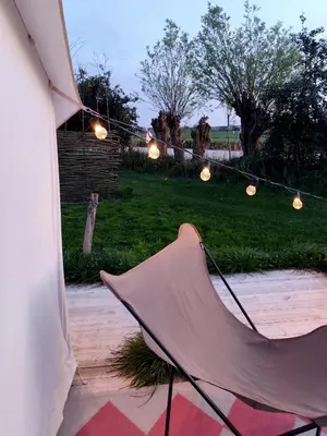a umbrella sitting on a patio with lights at Voedselbos Camping Koperwiek in Hazerswoude-Dorp