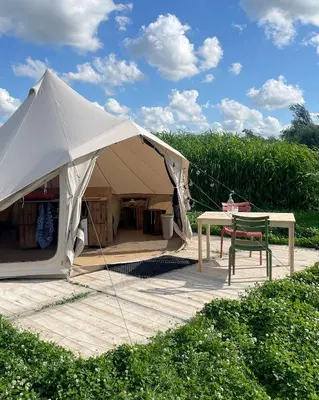 a white tent with a table in a field at Voedselbos Camping Koperwiek in Hazerswoude-Dorp
