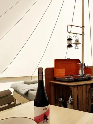 a bottle of wine on a table in a tent at Voedselbos Camping Koperwiek in Hazerswoude-Dorp
