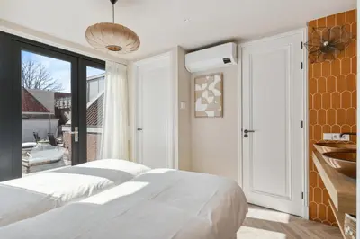 a bedroom with two beds and a balcony at STONEBRIDGE boutique apartments - City centre in Alkmaar
