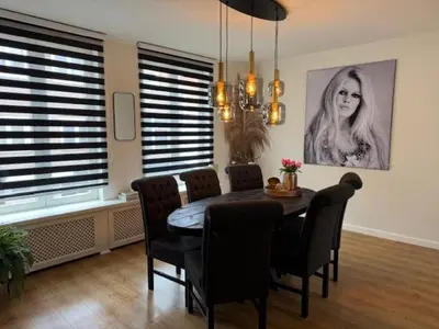 a dining room table with chairs and a picture of a woman at Sunny Beach in Zandvoort