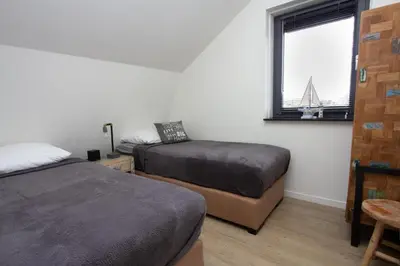a bedroom with two beds and a window at Villa Harry aan Zee in Egmond aan den Hoef