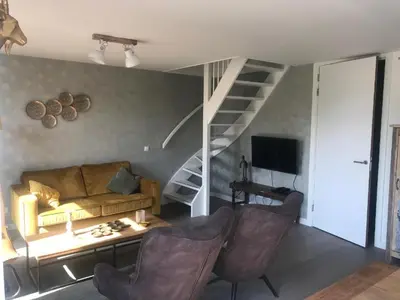 a living room with a couch and a staircase at Villa Harry aan Zee in Egmond aan den Hoef