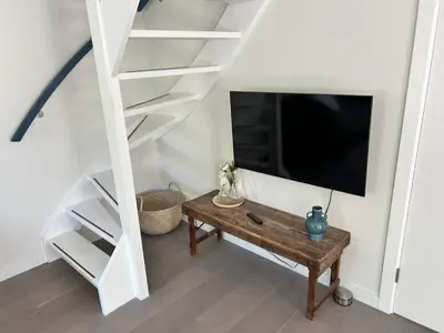 a living room with a tv and a wooden table at Villa Harry aan Zee in Egmond aan den Hoef