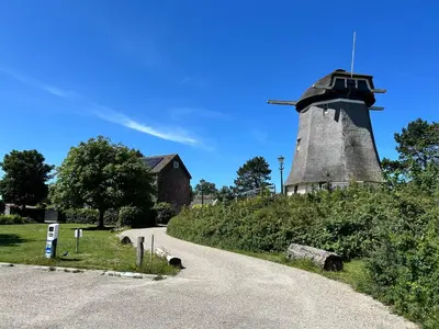 a windmill on a hill next to a road at Villa Harry aan Zee in Egmond aan den Hoef