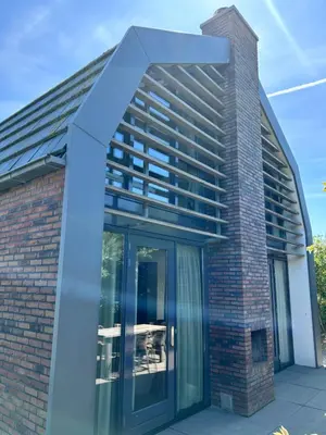 a building with glass doors on the side at Villa Harry aan Zee in Egmond aan den Hoef