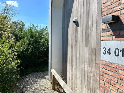 a wooden door with a bench next to a brick wall at Villa Harry aan Zee in Egmond aan den Hoef