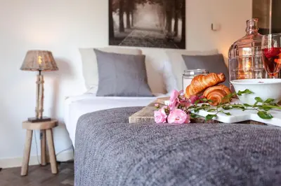 a bed with a tray of croissants and flowers on a table at Hajé Restaurant de Aalscholver in Lelystad