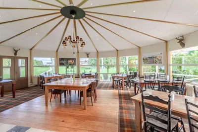 a dining room with tables and chairs and windows at Hajé Restaurant de Aalscholver in Lelystad