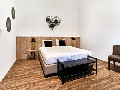 a bedroom with a large bed and a bench at Hajé Restaurant de Aalscholver in Lelystad