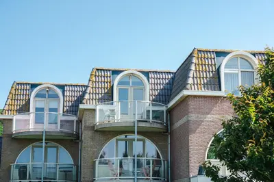 a brick building with windows and a roof at Gezellig 2 kamerappartement in Burgerbrug Dicht bij strand en natuur! in Burgerbrug