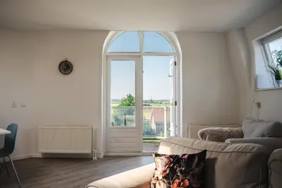 a living room with a couch and a large window at Gezellig 2 kamerappartement in Burgerbrug Dicht bij strand en natuur! in Burgerbrug