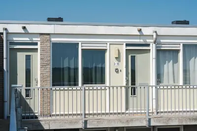 a building with a balcony with windows at Gezellig 2 kamerappartement in Burgerbrug Dicht bij strand en natuur! in Burgerbrug
