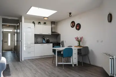 a kitchen with white cabinets and a table and chairs at Gezellig 2 kamerappartement in Burgerbrug Dicht bij strand en natuur! in Burgerbrug